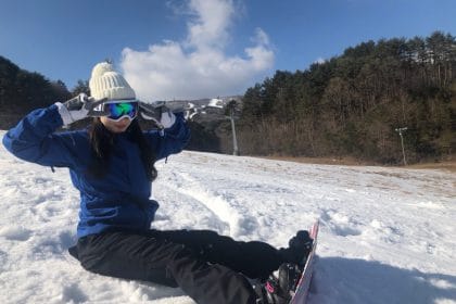 雪の中スノーボードに座る女性。