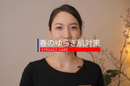 黒いシャツを着た女性が花の前に立っています。