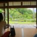 和室に座って庭を眺める女性。